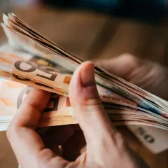 Hände halten einen Stapel Euro-Scheine. Dies könnte relevant sein für den **privatinsolvenz freibetrag**.