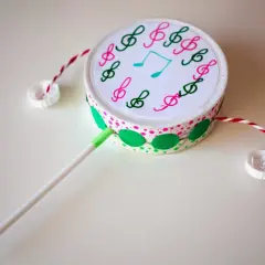 Tambor casero decorado con notas musicales, hecho con materiales reciclados. Un ejemplo de divertidos instrumentos musicales caseros.