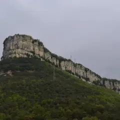 Imponent roca amb vegetació verda i una construcció al cim, recordant la Mare de Déu del Far.
