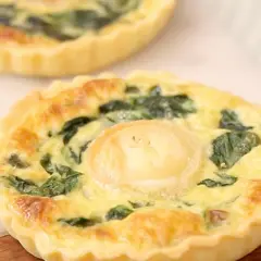 Une délicieuse quiche épinard chèvre, dorée et appétissante, avec une touche de fromage de chèvre au centre.
