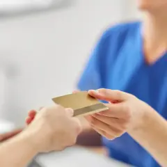 Dwie dłonie przekazują sobie złotą kartę.