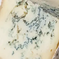 Un pezzo di taleggio con venature di muffa blu-verde che creano un disegno unico.