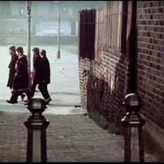 Czterech mężczyzn w płaszczach idzie ulicą Penny Lane.