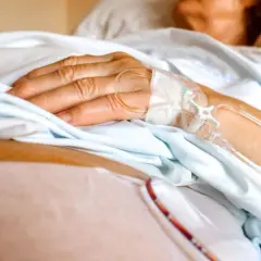 Dłoń pacjenta z wenflonem, przygotowująca się do podróży ze szpitala do hospicjum.
