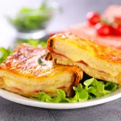 Deux croque monsieur gourmands, comme ceux de grand-mère, servis sur un lit de salade verte. Le fromage fondant et le pain doré donnent envie.