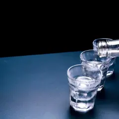 Ciepła wódka, dlaczego temperatura wpływa na odbiór paliwa? Trzy kieliszki wypełniane z butelki.