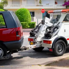 Une dépanneuse enlève une voiture rouge. Une amende pour stationnement illégal a peut-être été émise.