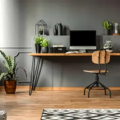 A modern desk setup with a computer, plants, and decorative items. This image shows how to hide cords on desk for a clean, organized workspace.