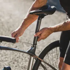 Rowerzysta reguluje wysokość siodełka, by uzyskać optymalną pozycję na rowerze szosowym.