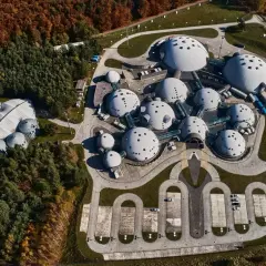 Widok z lotu ptaka na kompleks budynków przypominających obce struktury na planecie Alvernia. Dookoła lasy w jesiennych barwach.