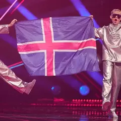 Dwóch artystów w srebrnych strojach prezentuje flagę Islandii na scenie Eurowizji.