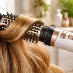 Suszarko-lokówka stylizuje blond włosy, tworząc efekt salonowy.