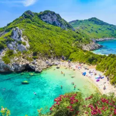 Malownicza zatoka z turkusową wodą i piaszczystą plażą. W maju Grecja zachwyca zielenią i kwitnącymi kwiatami.