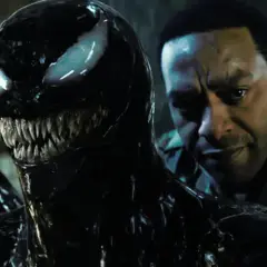 Venom, le symbiote noir aux dents acérées, se rapproche d'un homme au regard intense. Une scène prometteuse pour Venom 3.