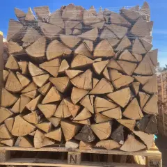 Un grand stère de bois, bien empilé et emballé sous plastique, prêt pour l'hiver.