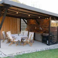 Jasna, betonowa podłoga w altanie z grillem i stołem zaprasza do biesiadowania.