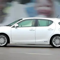 Biały Lexus CT200h w ruchu ulicznym, z rozmytym tłem i innymi samochodami.