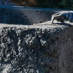 Ręka w rękawicy wygładza świeży beton. Zastanawiasz się, ile kosztuje worek cementu do takiej pracy?