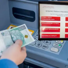 Wpłata BLIK w Santanderze. Ręka z banknotem 100 zł przy bankomacie, ekran wyboru źródła gotówki.