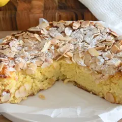 Delizioso dolce senza glutine con mandorle a lamelle e zucchero a velo, su un piatto bianco.