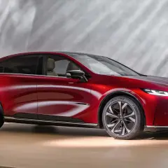 Czerwona Mazda 6e, ładowana elektrycznie, prezentuje nowoczesny design z eleganckimi liniami i dynamicznym profilem.