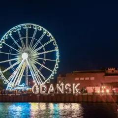 Nocne Gdańsk: diabelski młyn i wielki napis "GDAŃSK" to atrakcje dla dorosłych. Woda odbija światła miasta.