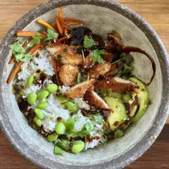 Apetyczny bowl z kurczakiem w panierce, ryżem, awokado, edamame i słodko-kwaśnym sosem.