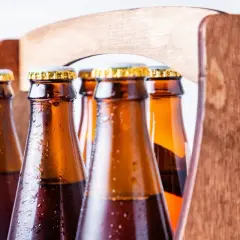 Zimne butelki piwa w drewnianym trayu. Z czego robi się piwo? Z chmielu, słodu i wody, a potem fermentuje.