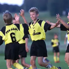 Dzieci w strojach piłkarskich świętują na boisku.