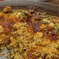 Paella de carne recién hecha, con arroz dorado, trozos de carne tierna, judías verdes y un delicioso socarrat crujiente.