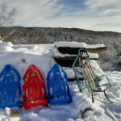 Gotowi na sylwester z dziećmi w górach! Trzy kolorowe sanki i jeden metalowy czekają na śnieżne szaleństwo.