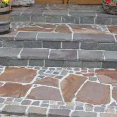 Stufen mit polygonalplatten verlegen. Große, unregelmäßige Steinplatten wechseln sich mit kleinen, quadratischen Pflastersteinen ab.
