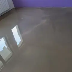 Lśniąca, świeża wylewka w neutralnym kolorze, odbijająca światło okien.