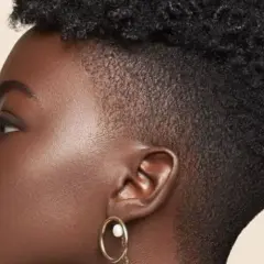 Perfil de mujer con cabello rizado y un moderno taper fade bajo.