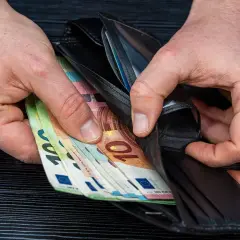 Ręce wkładają euro do portfela. Może to zarobki lakiernika w Niemczech.