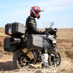 Motociclista con casco y equipo de aventura, listo para explorar. Como se llama el maletero de la moto, es un accesorio esencial para llevar todo lo necesario.