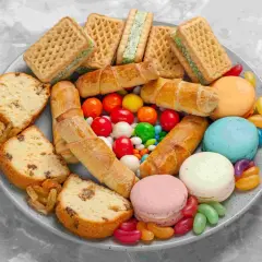 Talerz pełen słodyczy: ciasta, ciasteczka, makaroniki, cukierki żelki i draże.