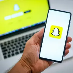 Chcesz wiedzieć, jak usunąć konto na Snapie? Na ekranie telefonu widać logo Snapchata, a na laptopie ekran logowania.