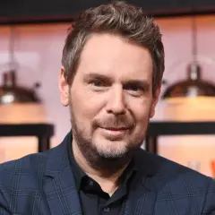 Uśmiechnięty mężczyzna w kratowaną marynarkę, z zarostem, wygląda jak skromny amaro.