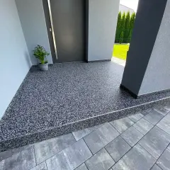 Nowoczesny kamienny dywan koszt 1m2 przy wejściu do domu. Elegancka, szara posadzka z drobnym kamyczkiem.