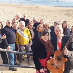 Famiglia riunita sulla spiaggia per festeggiare un compleanno con una "posteggia napoletana" e chitarra.