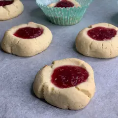 Nybakade glutenfria hallongrottor med sylt på bakplåtspapper. Perfekt fika!