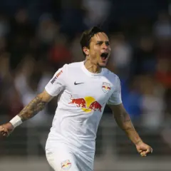 Piłkarz w białej koszulce z logo Red Bull świętuje bramkę. Wśród najlepszych brazylijskich piłkarzy, jego radość jest zaraźliwa.