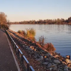 Spokojny brzeg rzeki, idealne miejsce na agroturystykę okolice Szczecina. Wędkarz na łódce, kaczka, ścieżka i jesienne liście.