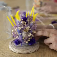 Un bouquet de fleurs séchées aux tons violets et jaunes, prêt à être protégé sous cloche. Un atelier créatif pour composer de jolies décorations.