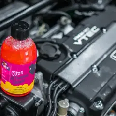 Flacone di detergente per il lavaggio motore auto, con motore Honda VTEC in background.