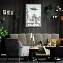 Gemütliches Wohnzimmer mit Akustikpaneelen an der Wand, einem Sofa, Sesseln, Pflanzen und einem Poster. Tolle Akustikpaneele Deko Ideen für ein stilvolles Zuhause.