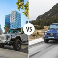 Szary Jeep Rubicon na tle miasta kontra niebieski Mercedes G-klasa na górskiej drodze.