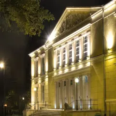 Elegancki budynek teatru w Jeleniej Górze nocą, oświetlony ciepłym światłem.