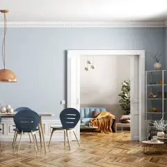 Helle Räume mit wandgestaltung streifen waagerecht in sanftem Blau. Ein Esstisch mit blauen Stühlen und eine gemütliche Sitzecke im Hintergrund.